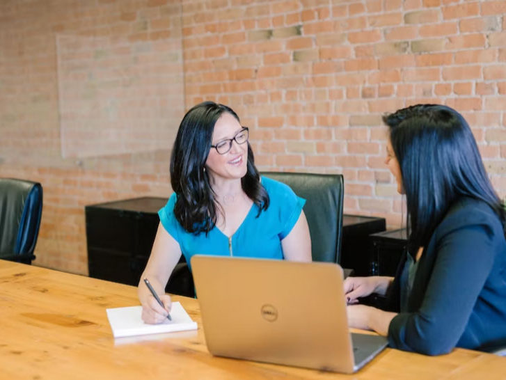 two people sitting at a computer talking