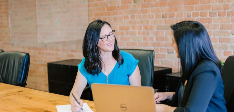 two people sitting at a computer talking