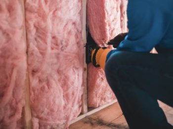a person putting insulation in a wall